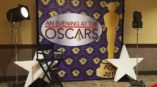 Purple and gold step and repeat banner for an evening at the oscars with white stars and lighting. 