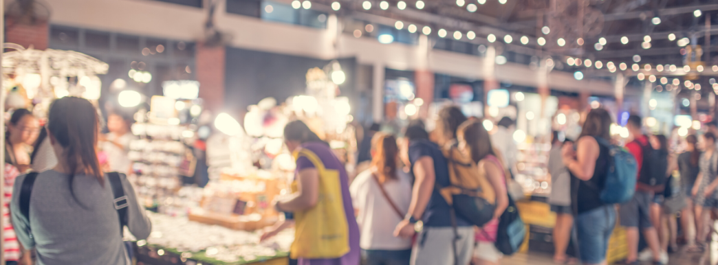 Gathering of people in looking at items on various tables.